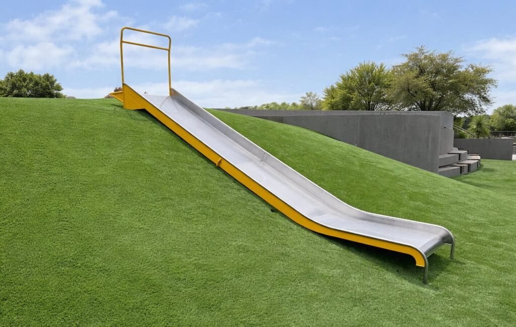 Wide flat bed stainless steel embankment slide on a park hillside by Landrec